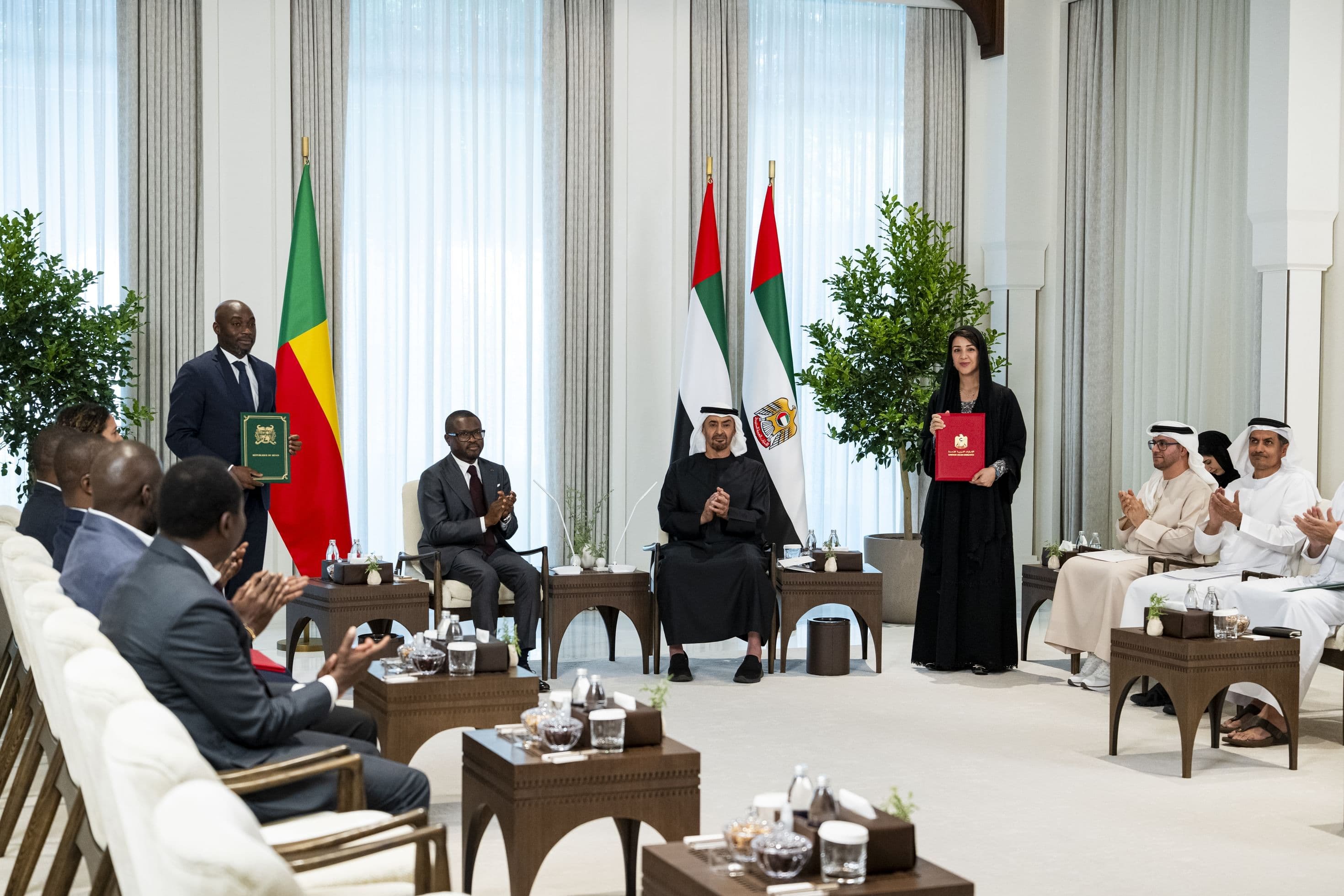 Trade ministers of Benin and the UAE hold up agreement folders as the two presidents applaud