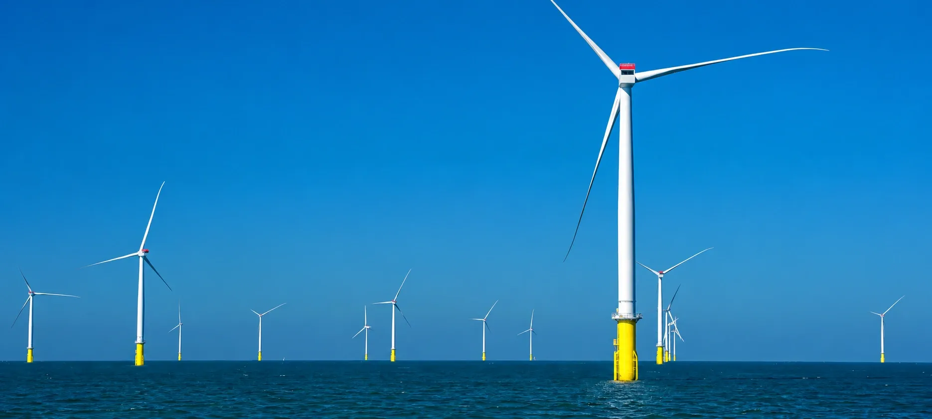 Offshore wind turbines standing in open sea under a clear blue sky